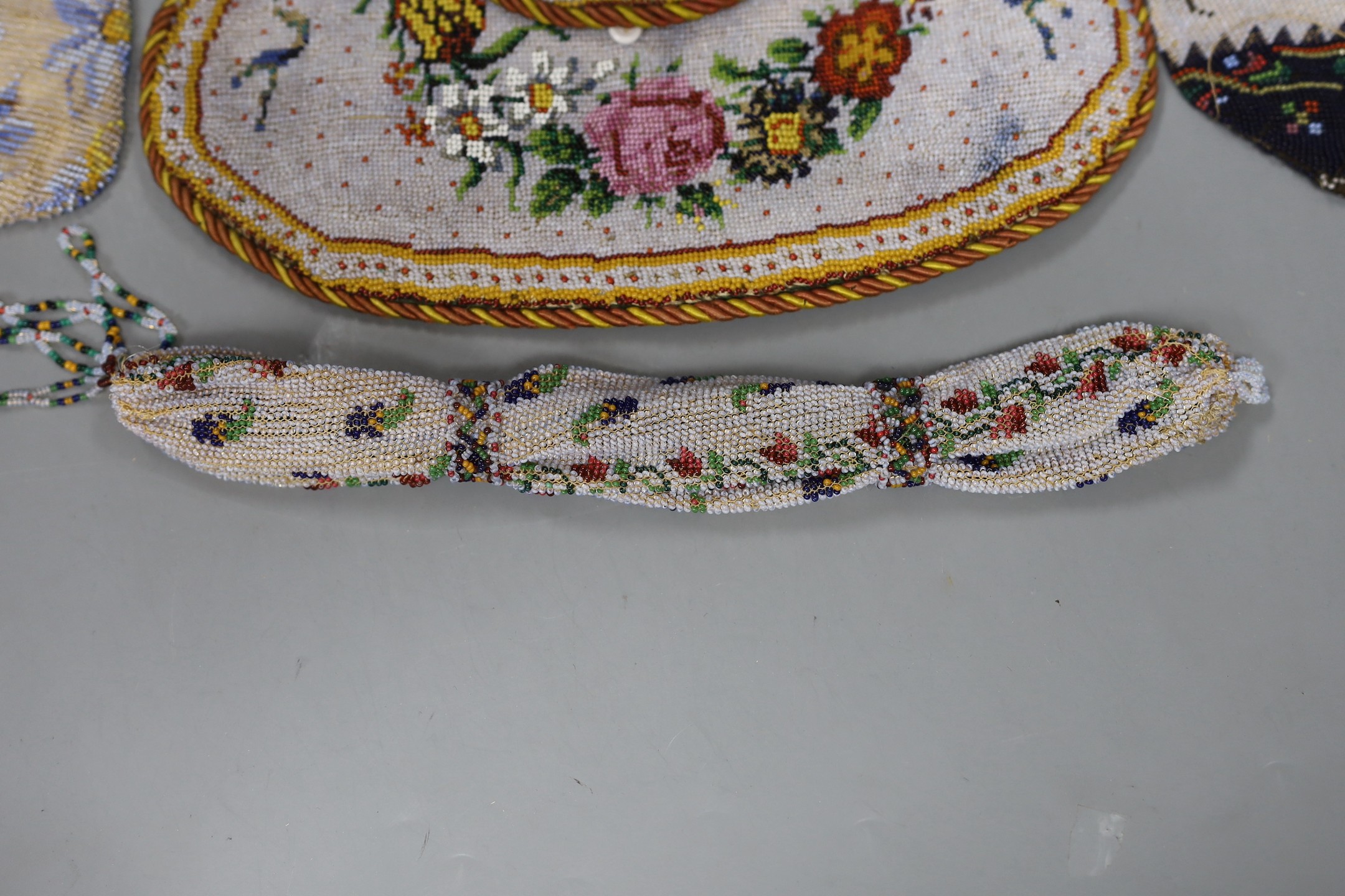 A 19th century shaped floral bead worked bag with corded edging and handle, an unusual bead worked misers purse and two small floral bead bags